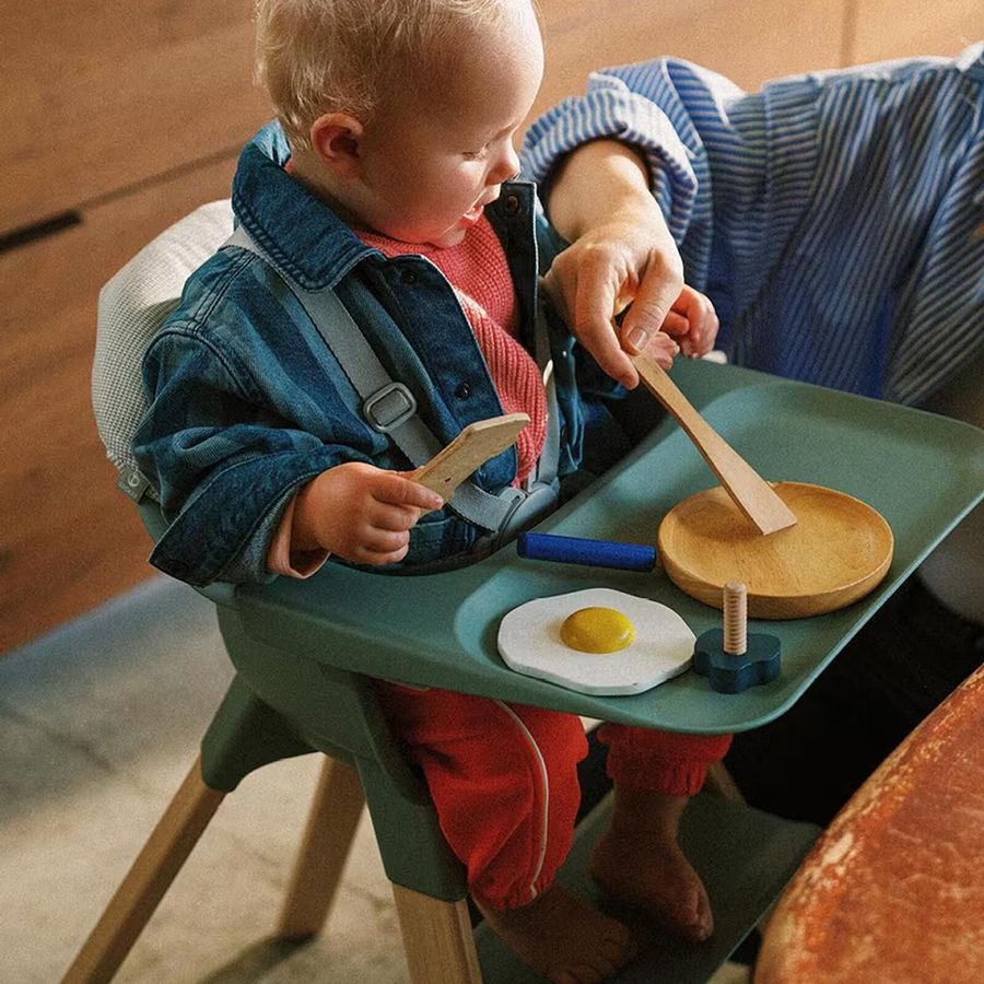 Barn som leker med mat på brettet til Clikk-stolen