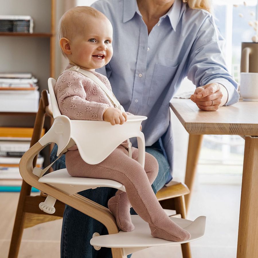 Smilende baby i Nomi-stol ved bordet