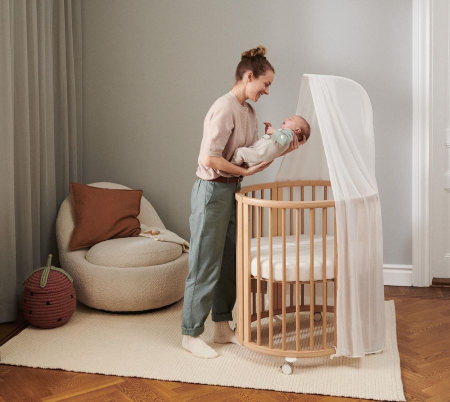 Mor med baby ved en Sleepi-seng på barnerommet